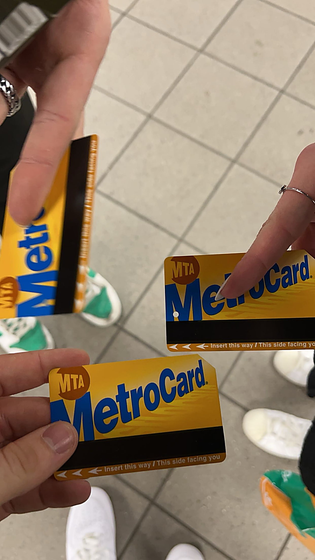 Drie handen met gele MTA MetroCards in de metro van New York