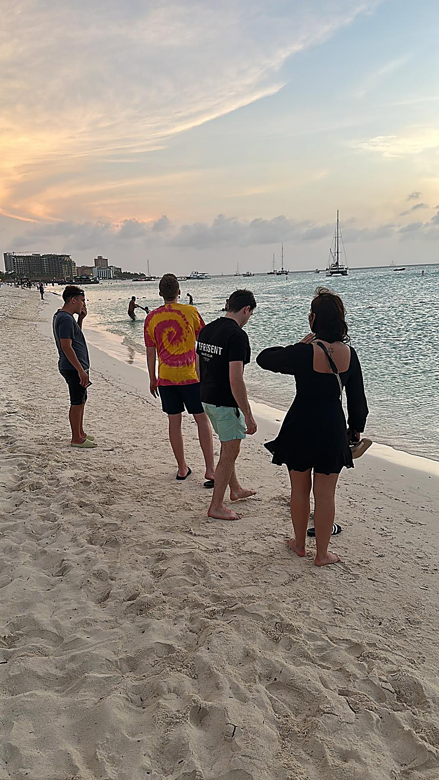 Vrienden wandelen bij zonsondergang over het strand van Aruba